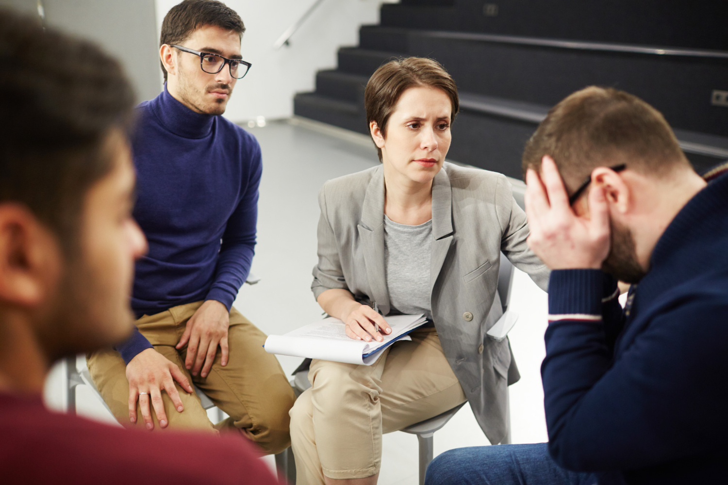 Group therapy session with a woman comforting a distressed man.